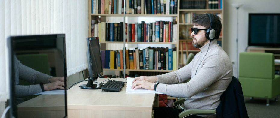 man with sunglasses and headphones sitting at a computer